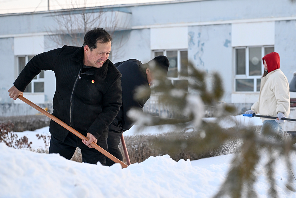 2月9日,在伊犁哈萨克自治州新源县,木沙江·海拉特(前)在克热格塔斯村党群服务中心和当地干部一起清理积雪。新华社记者 王菲 摄