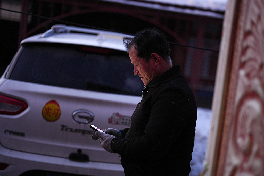 2月9日,在伊犁哈萨克自治州新源县,木沙江·海拉特在自家的院子里查看乡亲发来的电焊需求。新华社记者 辛悦卫 摄