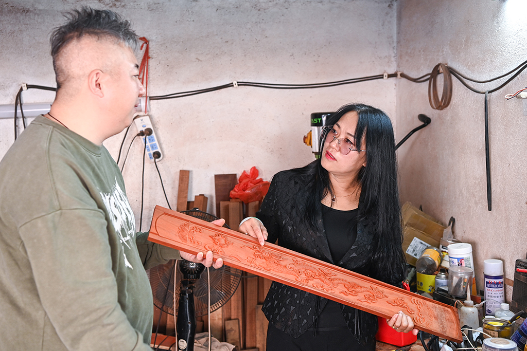 2月7日,在广西东兴市,苏海珍(右)与独弦琴制作匠人讨论琴身材质和纹饰。