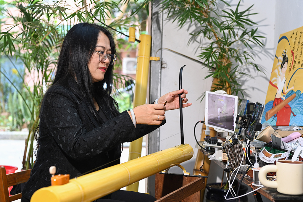 2月7日,苏海珍在位于广西东兴市的工作室内通过手机直播向网民演奏独弦琴。