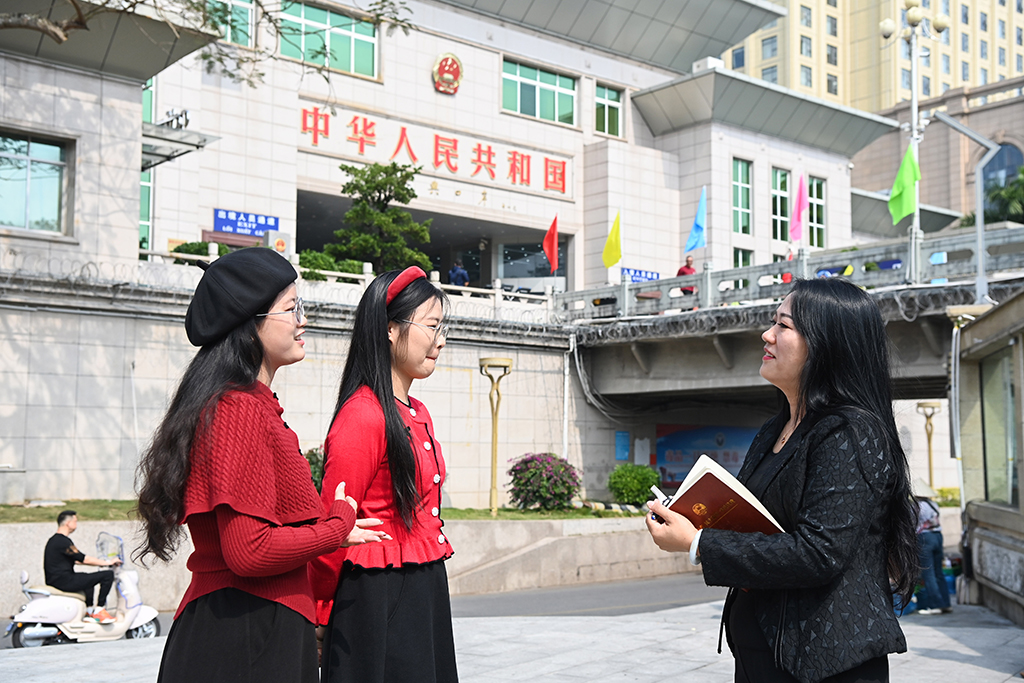 2月7日,苏海珍(右)在东兴口岸附近向外地游客了解旅游体验。