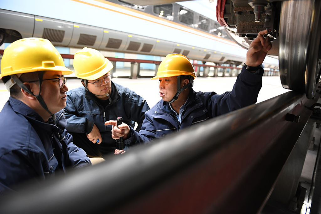   1月14日，在位于中国铁路西安局集团有限公司西安动车段的动车组检修库，董宏涛（右）和青年职工一起检修动车组列车。