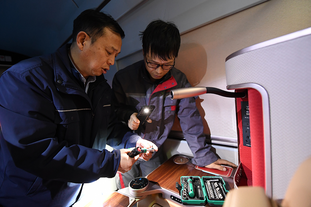  1月14日，在中国铁路西安局集团有限公司西安动车段动车组检修库的待检列车上，董宏涛（左）和同事探讨业务。