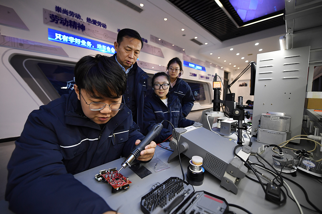 1月14日,在位于中国铁路西安局集团有限公司西安动车段的董宏涛国家级技能大师工作室,董宏涛(左二)指导工作室成员研究检修业务。