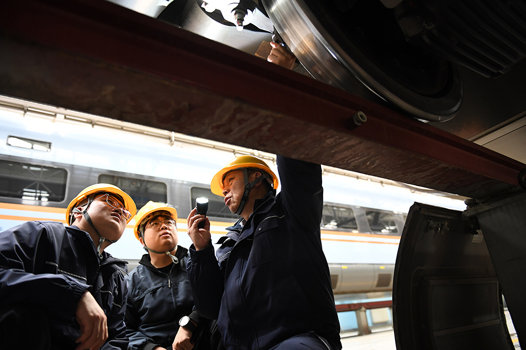  1月14日，在位于中国铁路西安局集团有限公司西安动车段的动车组检修库，董宏涛（右）和青年职工一起检修动车组列车。