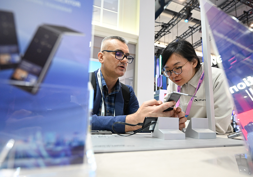 3月2日,在西班牙巴塞罗那,人们在科大讯飞展台体验翻译设备。