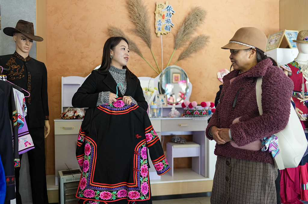 2月10日,金瑞瑞在自己的工作室内为顾客介绍彝绣服饰。