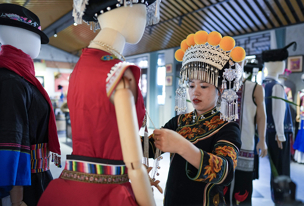 2月9日，金瑞瑞在自己的工作室内打理展出的彝绣服饰。