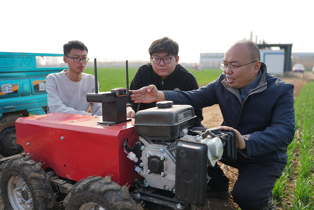 3月9日,山东农业大学副教授陈国庆(右)和团队成员在调试农田作业通用机器人。