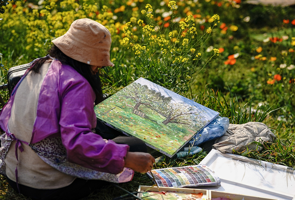 3月10日，一名油画爱好者在昆明名花谷写生。