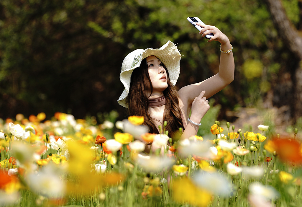 3月10日，一名游客在昆明名花谷的虞美人花丛旁拍照。
