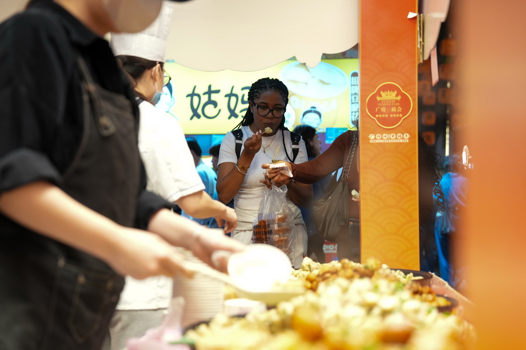 3月12日，在广州市越秀区北京路步行街区举办的美食庙会上，外国游客在品尝美食。
