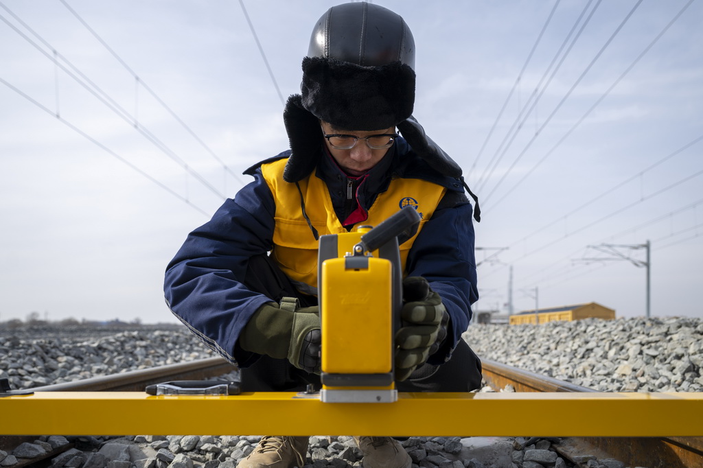 3月13日,工人在哈伊高铁绥化南站施工现场进行测量作业。