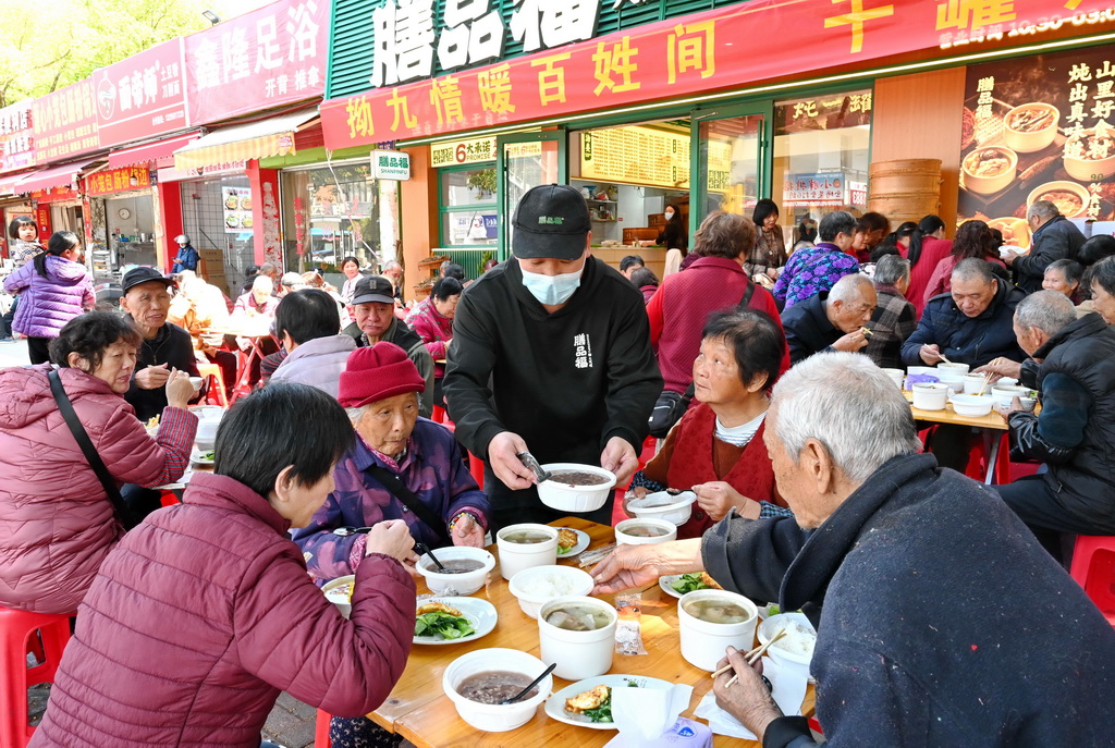 3月17日，在福州市仓山区后巷路，一位餐饮店主（中）为老人送上“拗九粥”。