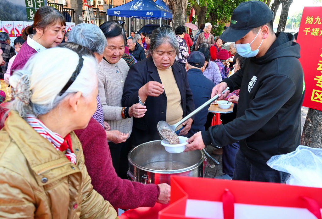 3月17日,在福州市仓山区后巷路,一位餐饮店主(右一)向老人赠送“拗九粥”。