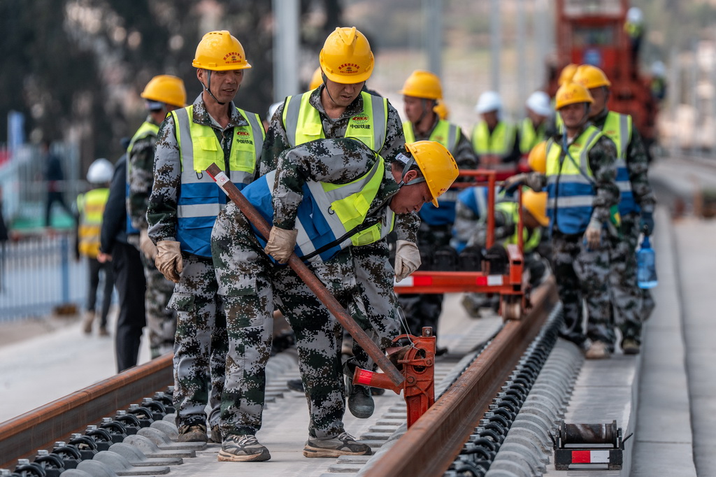 3月18日,工人在渝昆高铁施工现场进行铺轨作业。