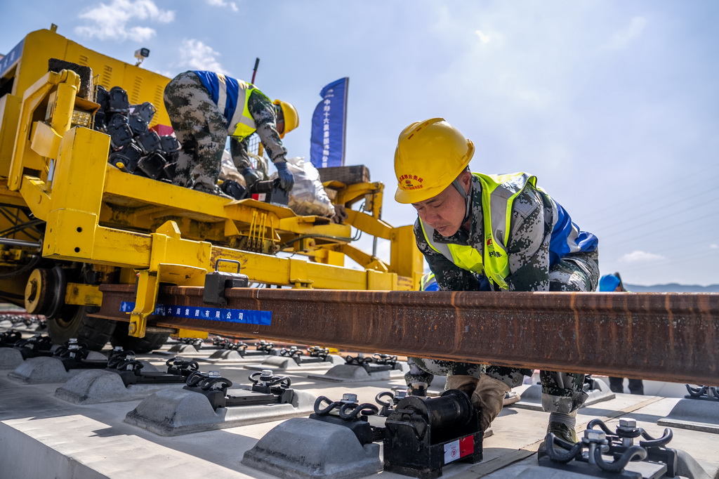 3月18日,工人在渝昆高铁施工现场进行铺轨作业。