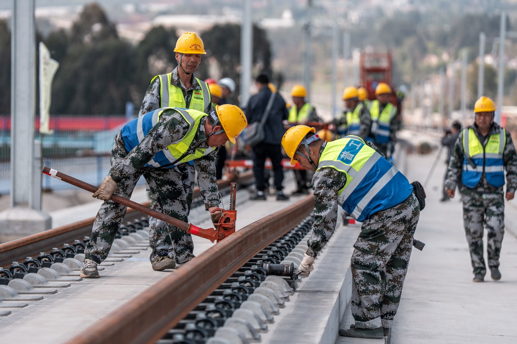 3月18日,工人在渝昆高铁施工现场进行铺轨作业。