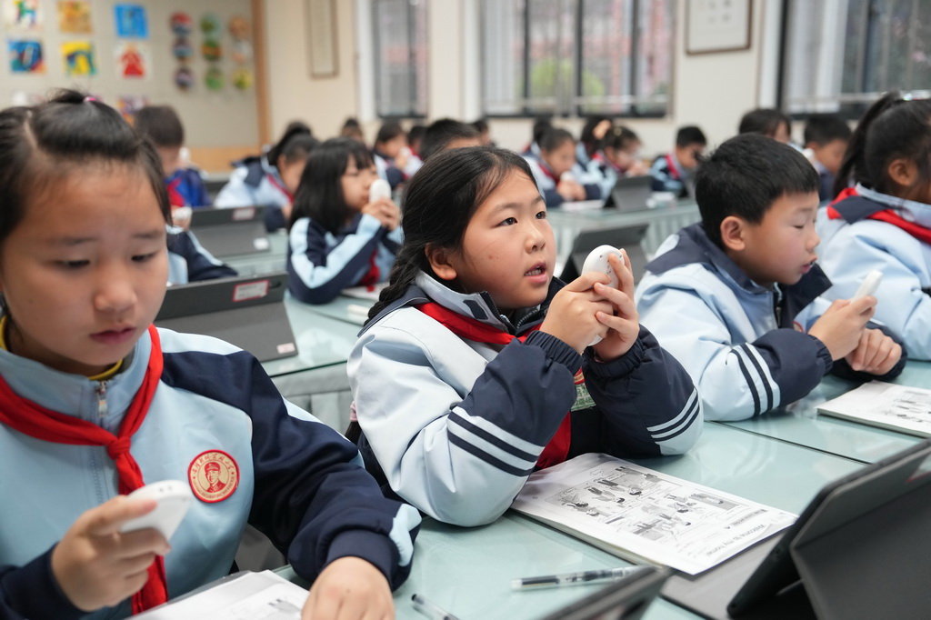 3月17日，在湖南湘江新区雷锋小学，学生在英语课上手持语音答题器回答老师问题。他们的答题录音将实时同步至教学终端，教师能结合人工智能的学情分析功能，精准掌握每位学生的发音情况。