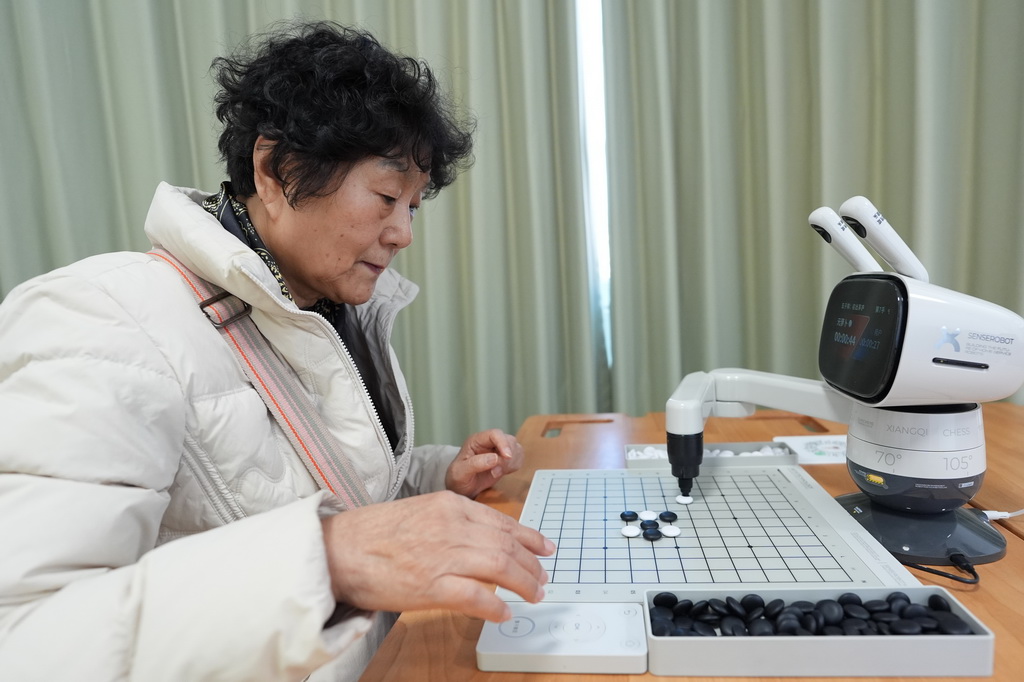 在智慧康养机器人养老驿站内，一名社区居民与一款机器人下五子棋（3月18日摄）。