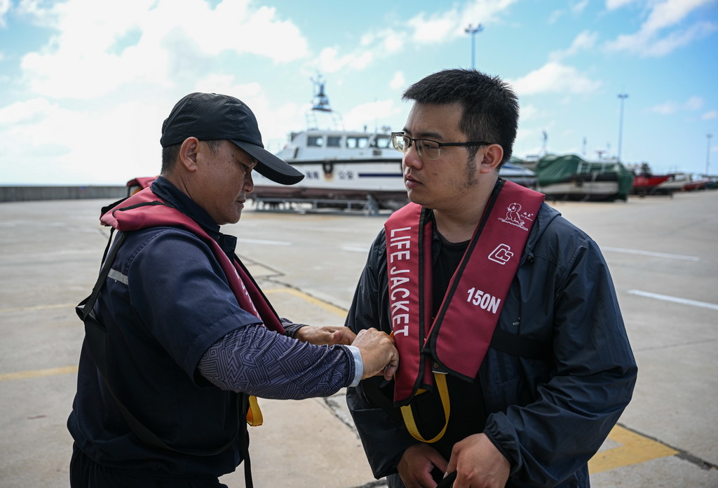 3月19日，海上交通保障船工作人员（左）协助乘客穿戴救生衣。新华社记者 蒲晓旭 摄