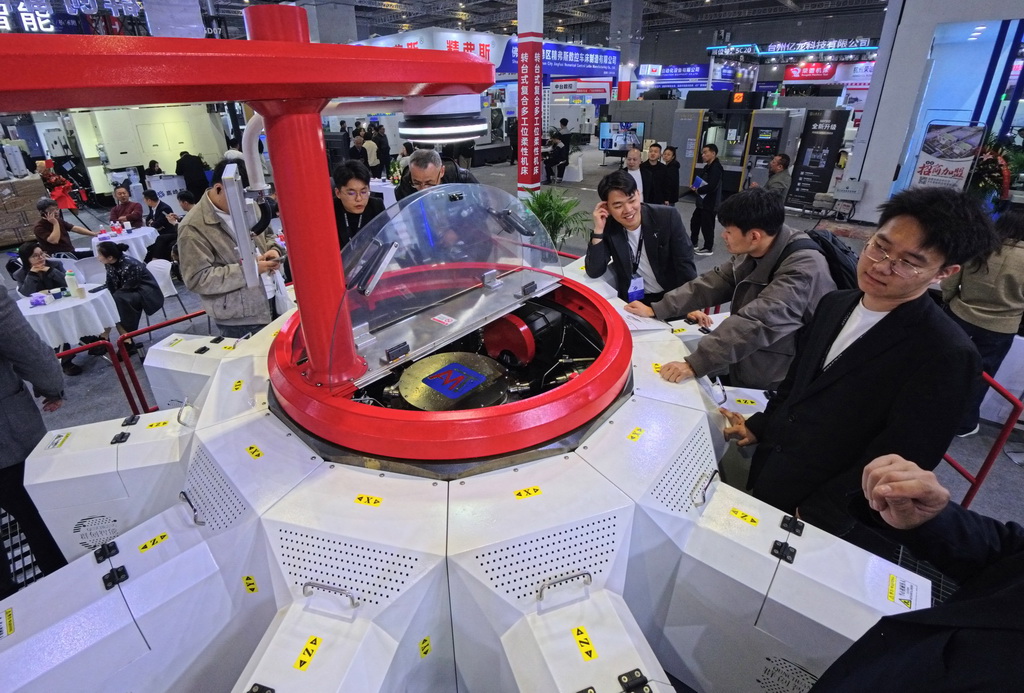 3月23日,参观者在一款转台式多工位柔性复合机床展品旁观看交流。