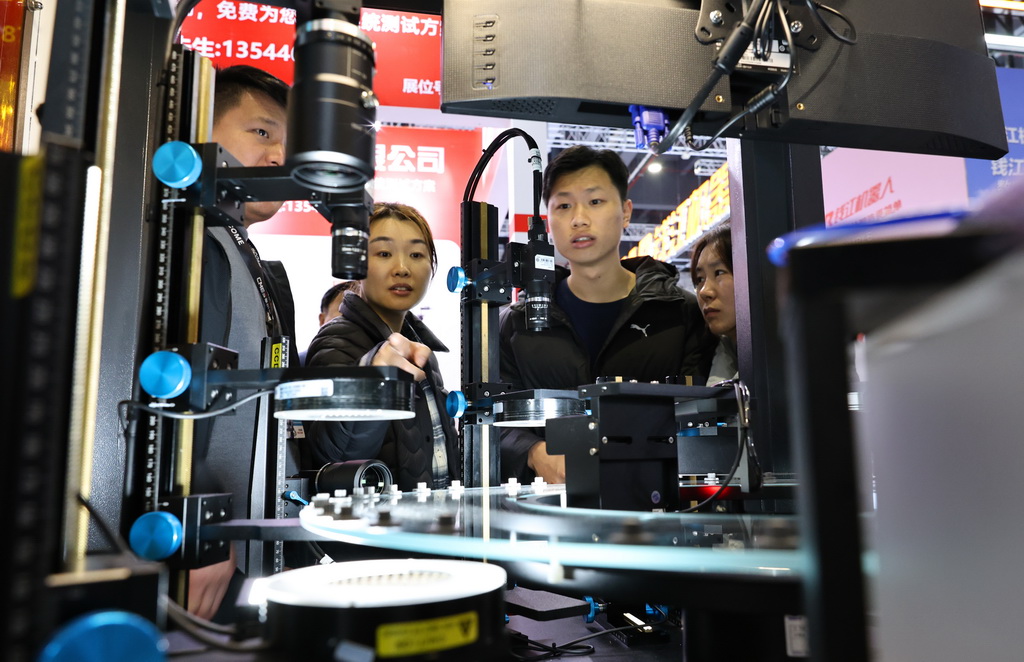 3月23日,参观者在一台光学影像自动化检测设备前驻足观看。