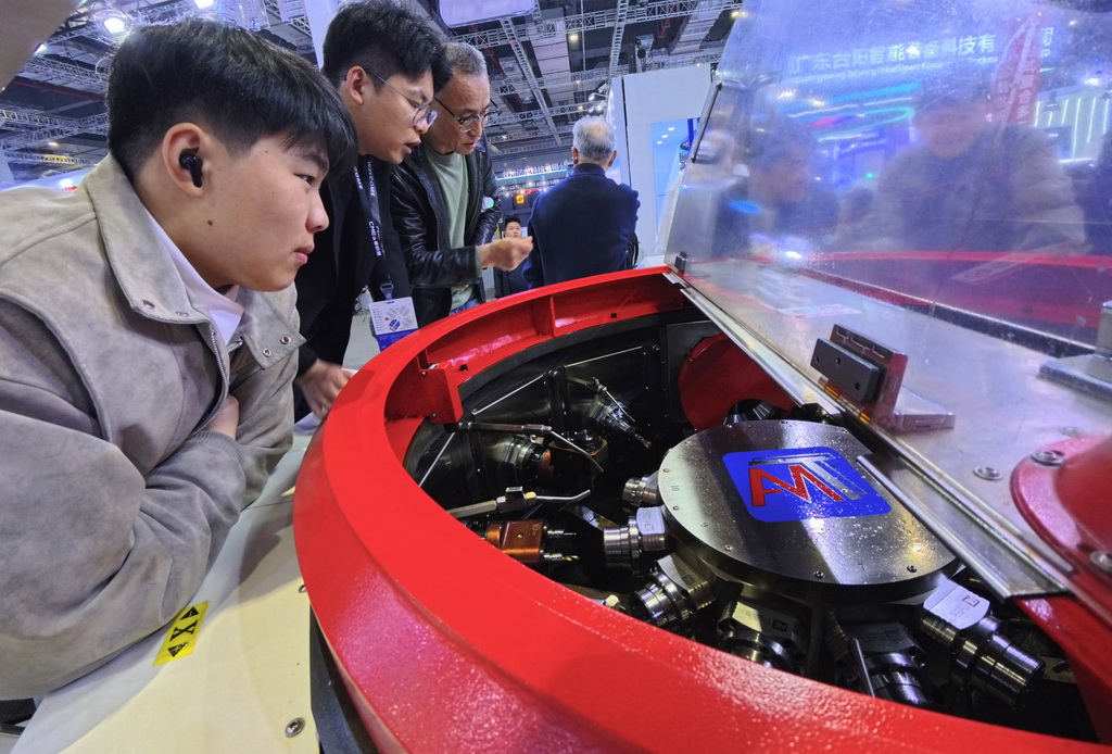 3月23日,参观者近距离观看一款转台式多工位柔性复合机床展品。