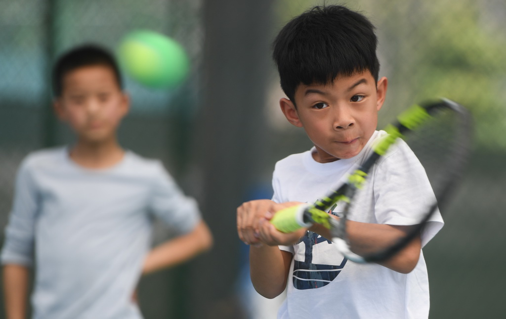 在湖北省京山市文峰公园网球场,一名小朋友在打网球(2024年3月22日摄)。新华社记者 杜子璇 摄