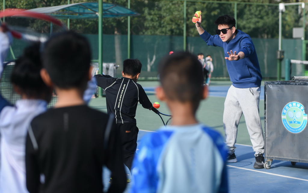 在湖北省京山市文峰公园网球场,教练指导孩子们打网球(2024年3月21日摄)。新华社记者 杜子璇 摄