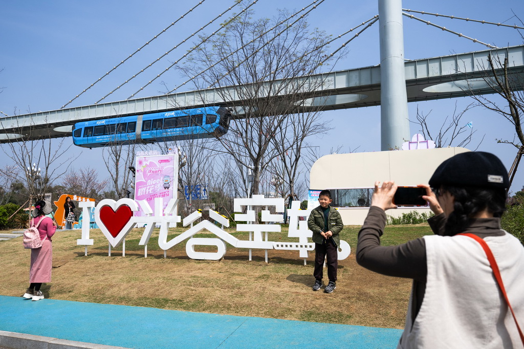 3月21日，游客在一列空轨列车驶过时拍照留念。