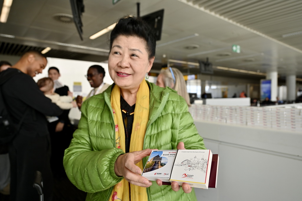 3月24日,在比利时布鲁塞尔国际机场,搭乘首航航班的乘客展示首航纪念品。