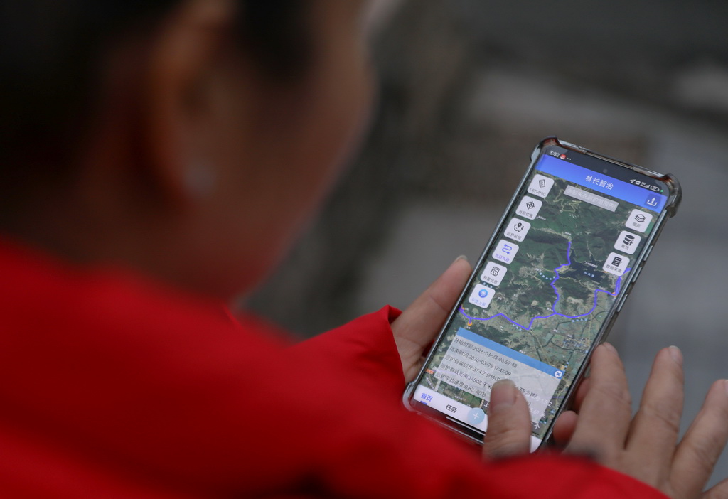 3月23日,在浙江省宁波市镇海区九龙湖镇,一名护林员查看手机上的巡护路线记录。该镇护林员须使用手机应用程序,在巡护点打卡,并记录巡护路线、时长等信息,方便查漏补缺。新华社记者 杜潇逸 摄