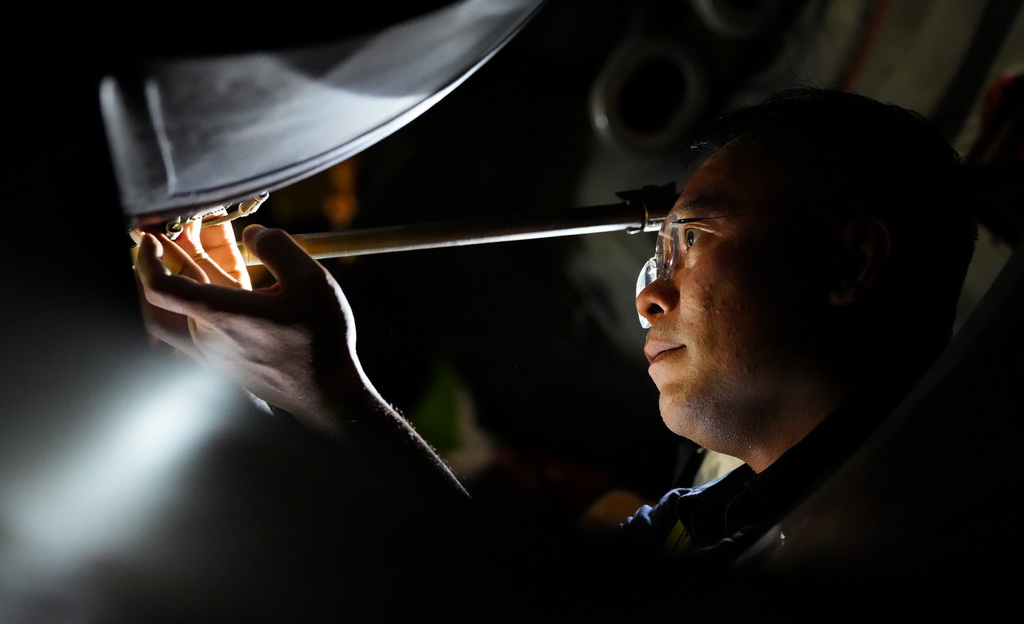 在海口美兰国际机场停机坪上,南航工程技术分公司机务工程师对“消博号”彩绘飞机进行深度检查(4月4日摄)。