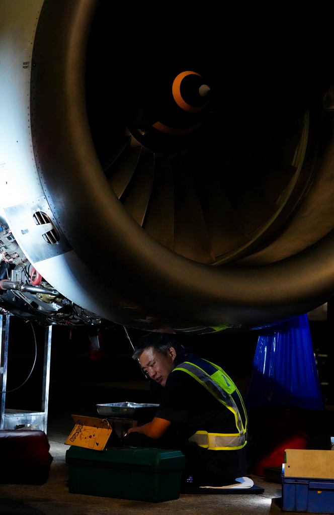 在海口美兰国际机场停机坪上,南航工程技术分公司机务工程师对“消博号”彩绘飞机进行深度检查(4月4日摄)。