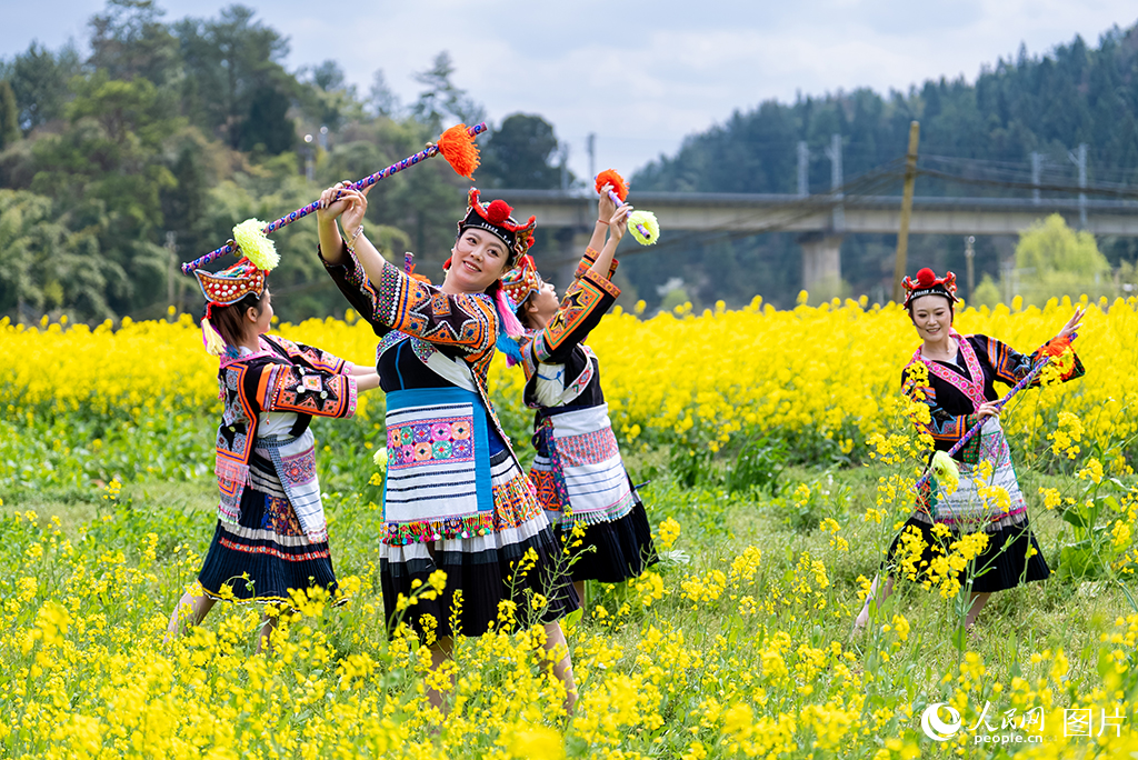 2026年3月13日,贵州贵阳乌当区新堡布依族乡,身着苗族传统服饰的姑娘在油菜花田里跳花棍舞。人民网记者 涂敏摄