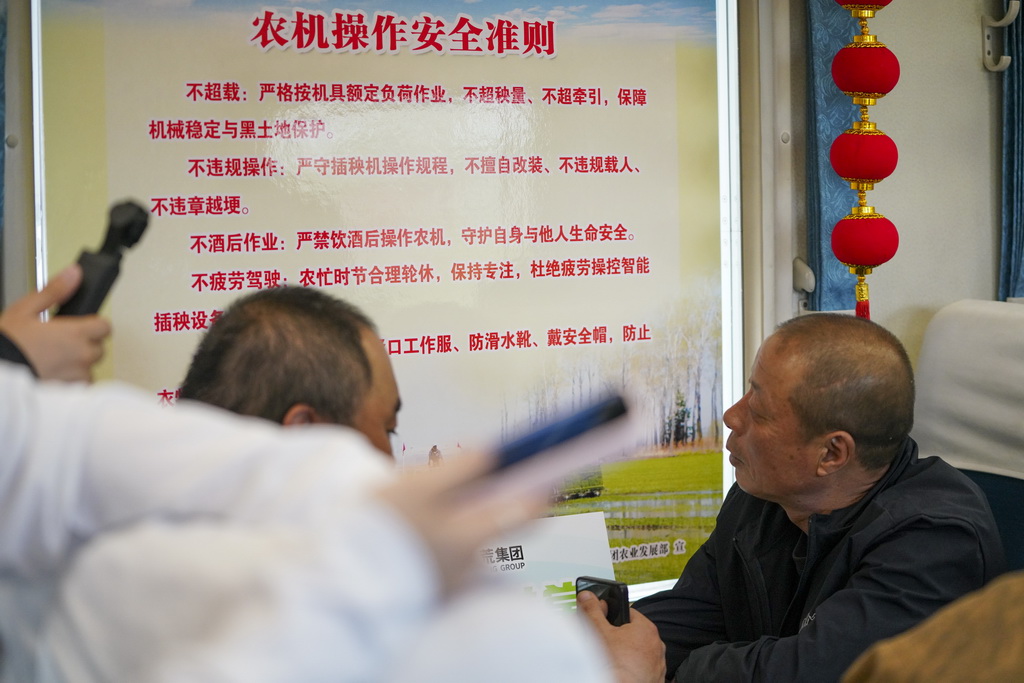 5月13日，乘客在K5153次“插秧专列”上查看农机安全操作知识。