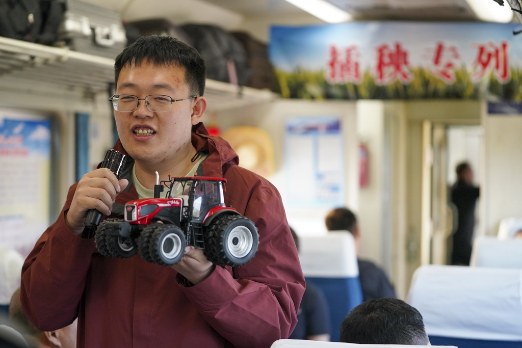 5月13日,一名农技人员在K5153次“插秧专列”上为乘客讲解农机操作技术与设备运维知识。