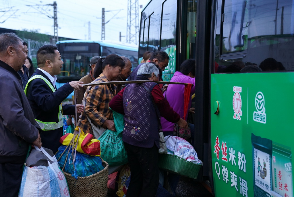 菜农在江西省南昌县向塘镇浃溪村的公交站点上车(5月9日摄)。
