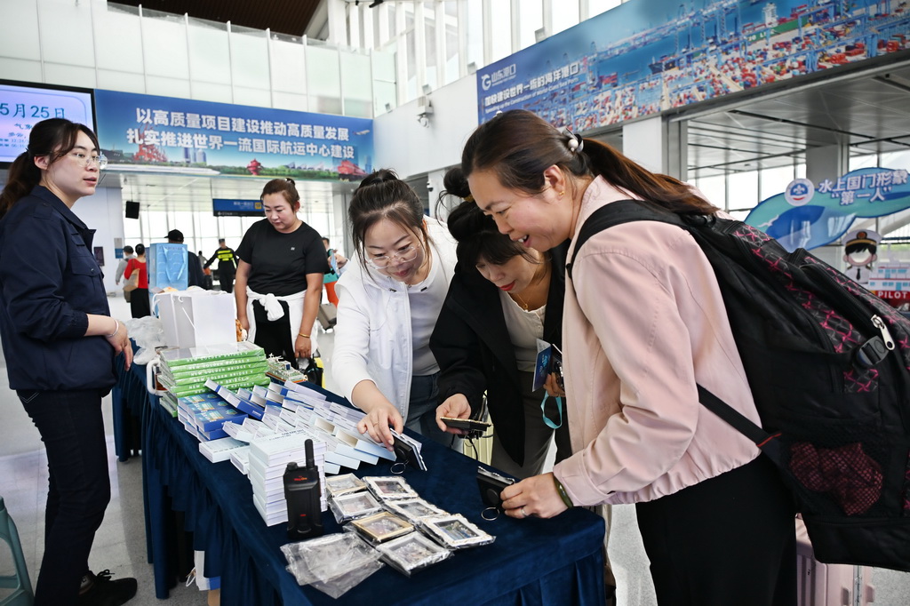 5月25日，游客在青岛邮轮母港候船大厅选购邮轮文创商品。
